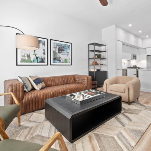 Model living room at The Monde apartments for rent in Scottsdale, AZ featuring wood grain floor paneling and a leather couch.