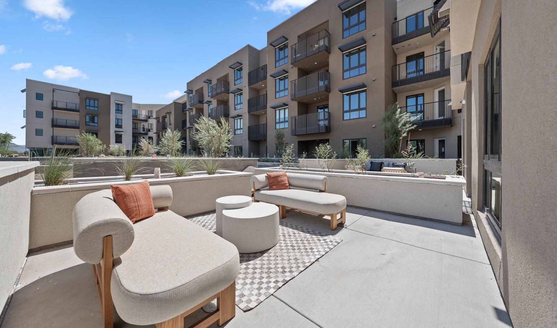 Outside patio for fun and socializing The outdoor lounge at The Monde apartments for rent in Scottsdale, AZ, featuring cushioned lounge chairs and potted plants.