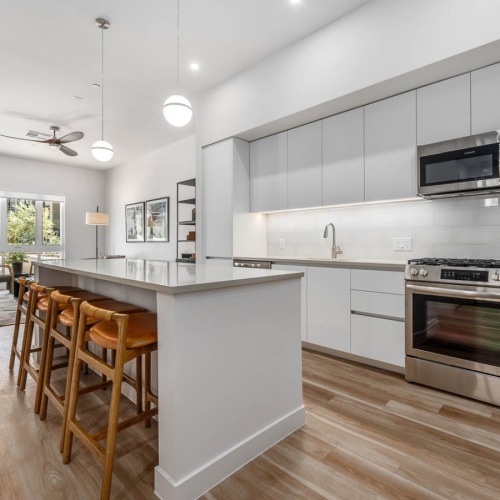 Resident lounge and kitchen at The Monde apartments for rent in Scottsdale featuring counter seating and wood grain flooring.